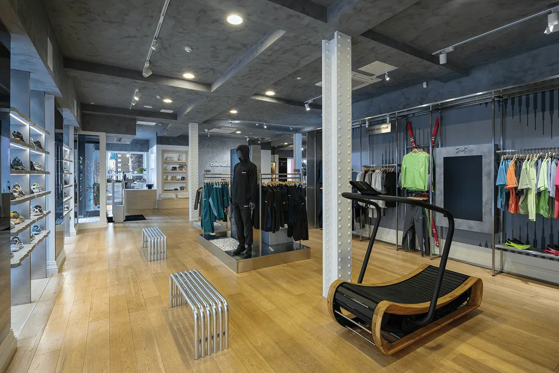 Main sales floor of the Drip Moda Liverpool retail fit-out project, featuring bespoke stainless steel hanging rail display systems, handcrafted concrete shelving with integrated LED lighting, limewash wall finishes and custom shopfitting by Bobblehat.